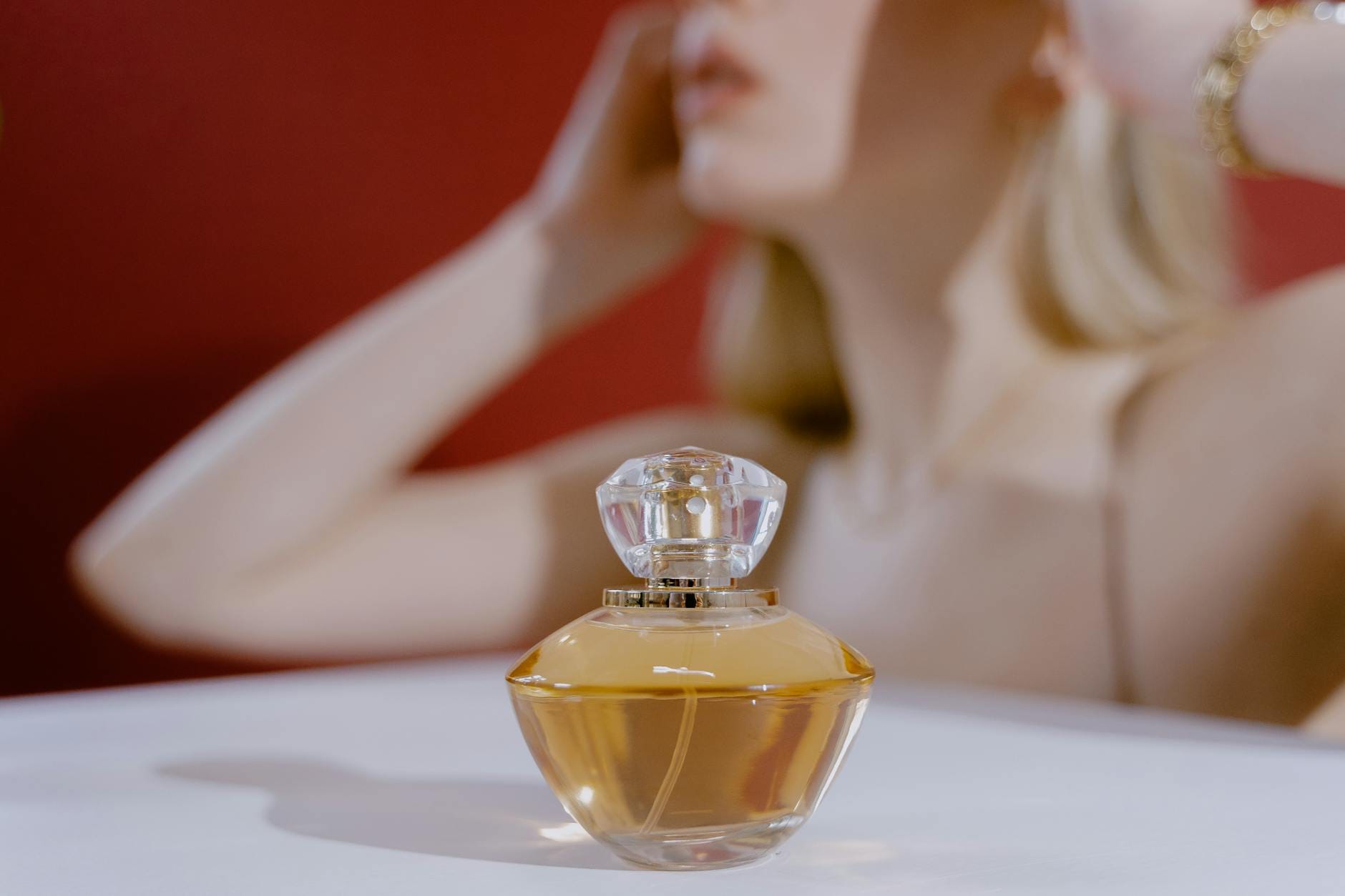 Elegancki flakon perfum z rozmytą sylwetką kobiety w tle